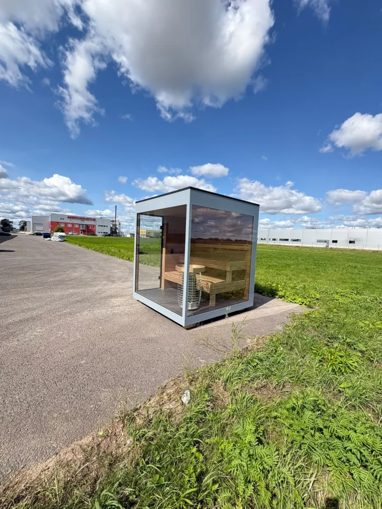 New glass-fronted outdoor sauna by Nordik Wellness seen across the field