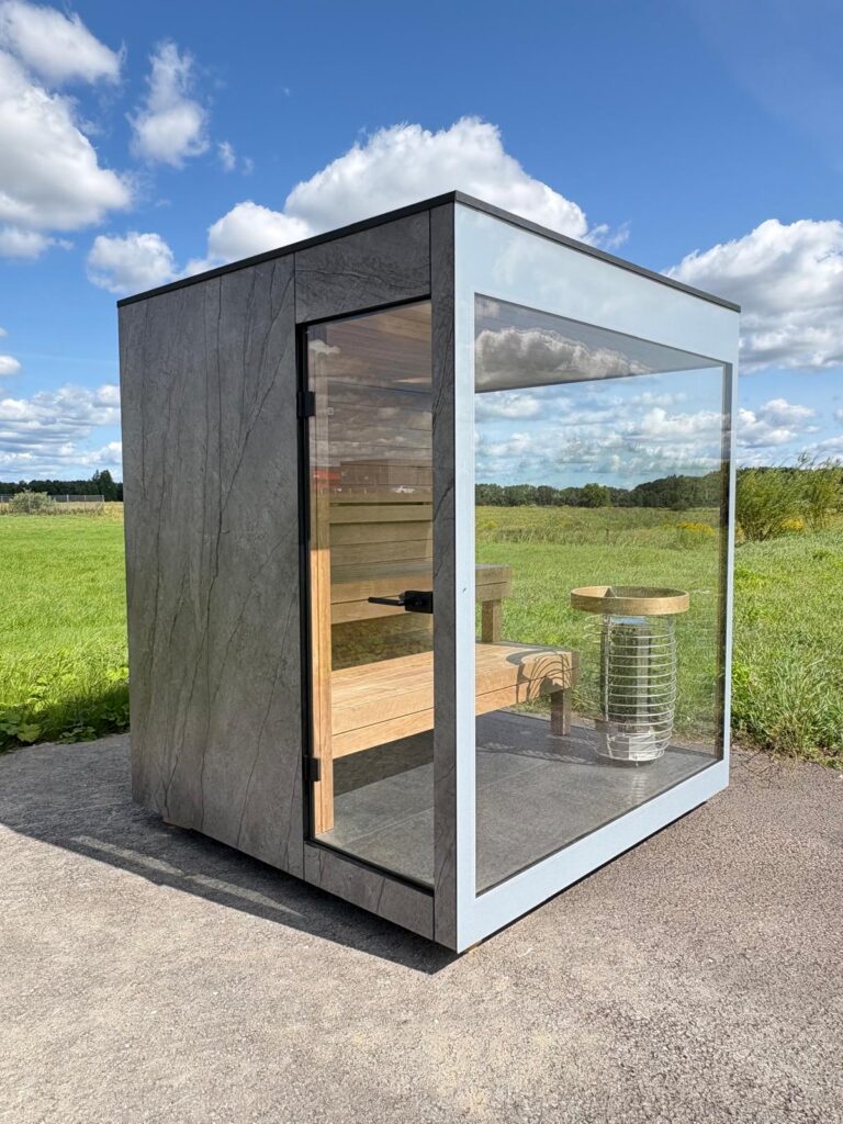 New outdoor sauna by Nordik Wellness with stone-effect cladding, glass walls and timber benches