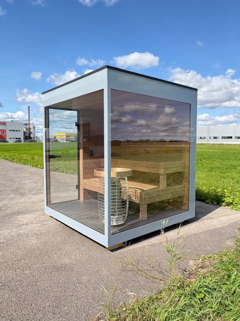 New glass-walled outdoor sauna by Nordik Wellness with a pale frame and timber benches