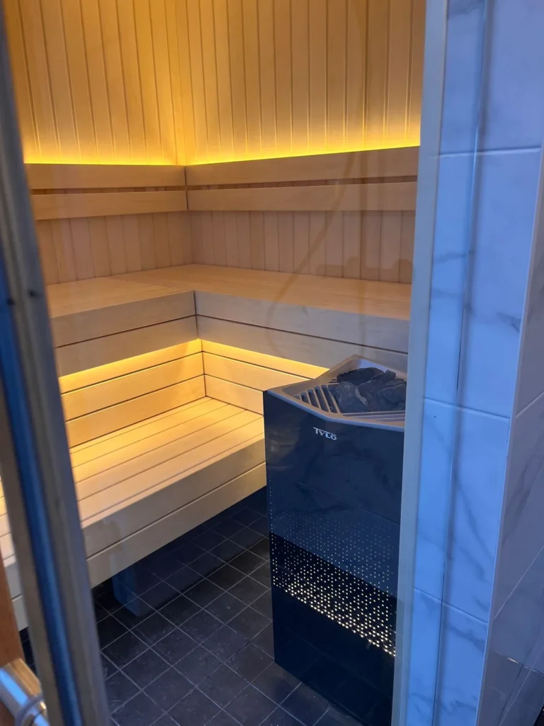 Finnish sauna with pale timber benches and a stone-filled heater